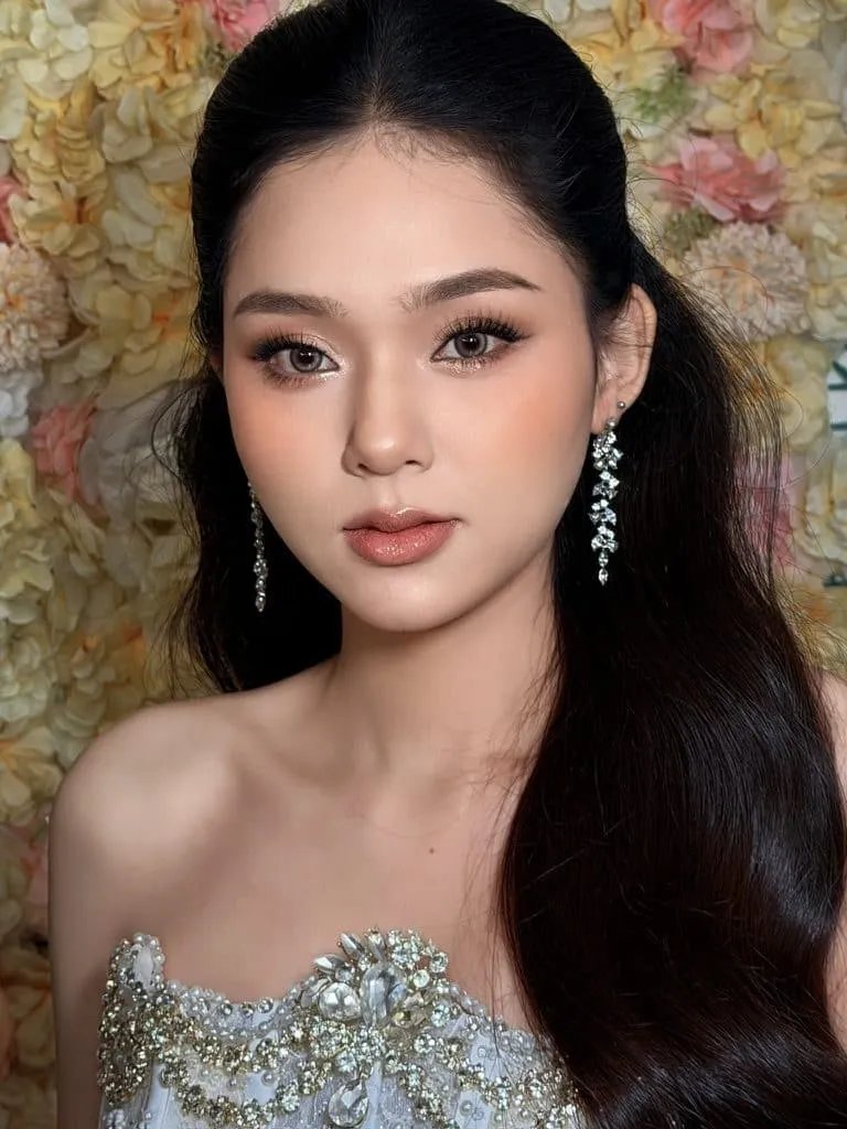 Cô dâu tóc đen buộc nửa, bông tai đá dài, váy đính đá trước tường hoa, KINKAY Sài Gòn