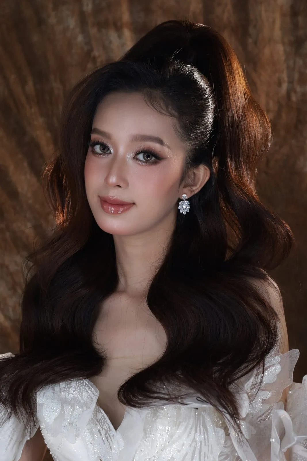 Cô dâu tóc búi cao phồng uốn sóng, váy cưới ren trắng, mắt nâu nhạt, makeup bởi KINKAY, TP.HCM