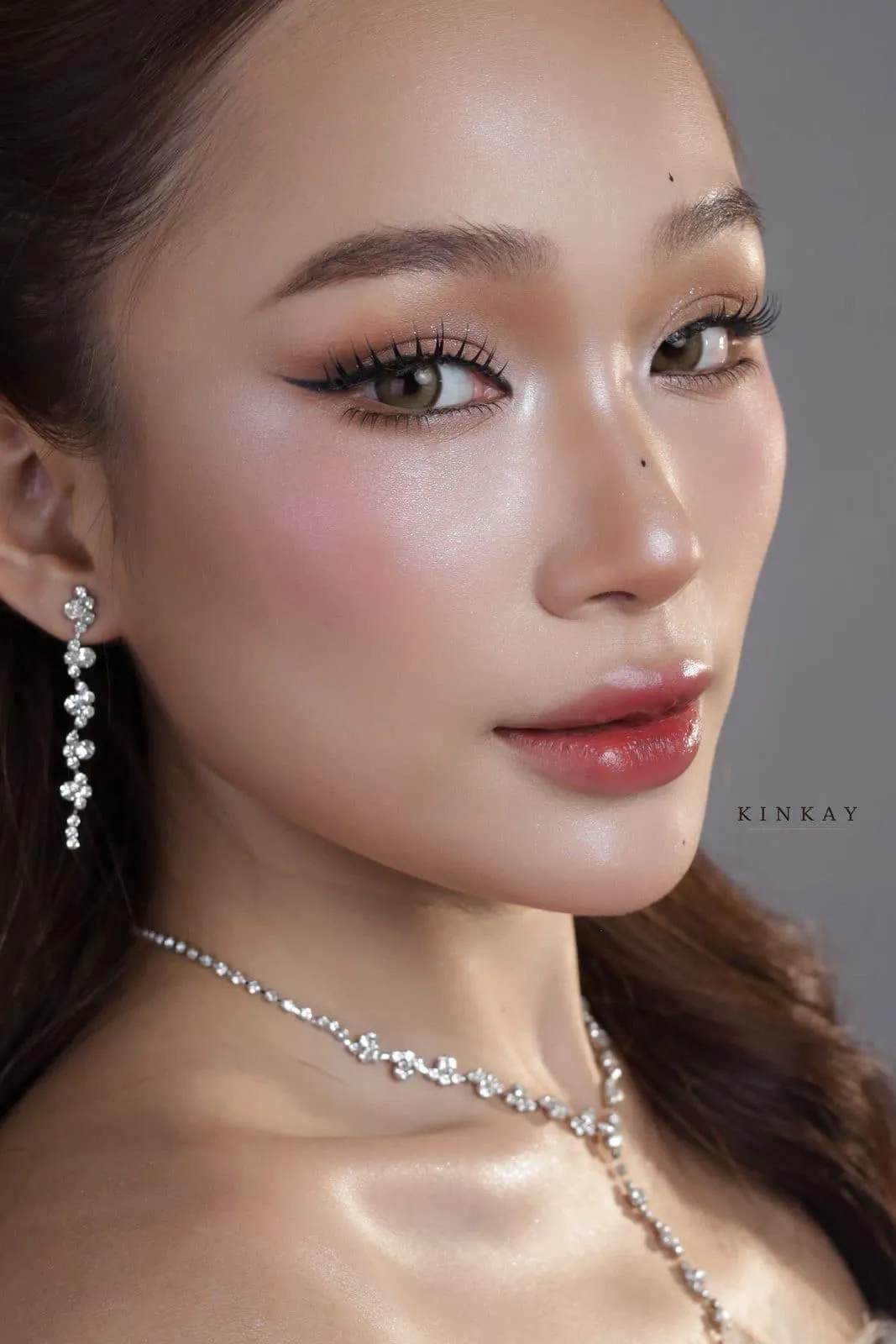 Cận cảnh má hồng và mắt nâu khói nhẹ, vòng cổ đá mảnh, vai trần, KINKAY Sài Gòn